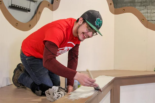 Valu member helping paint the Herschell Carrousel Factory Museum