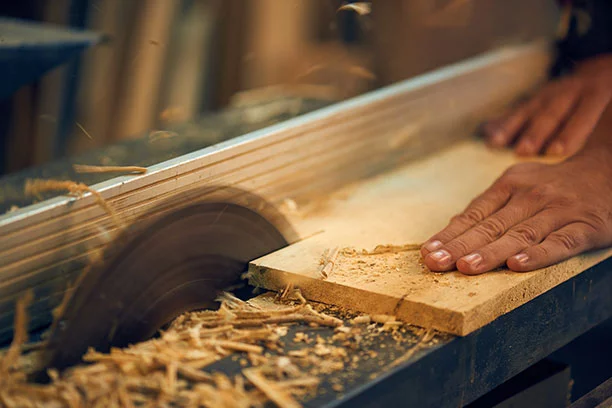 Person cutting a piece of wood on a table saw