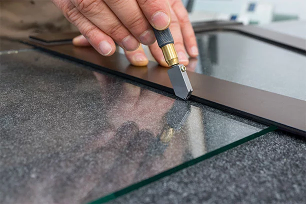 Man cutting glass using a straight edge