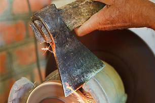Man sharpening an axe head on a grinder