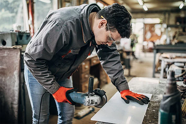 Man wearing personal protection while cutting a piece of plexiglass