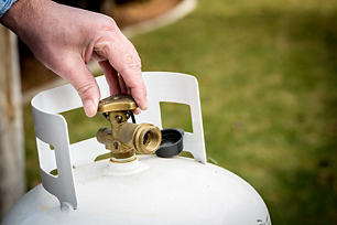 A close-up of someone turning the knob on a propane tank