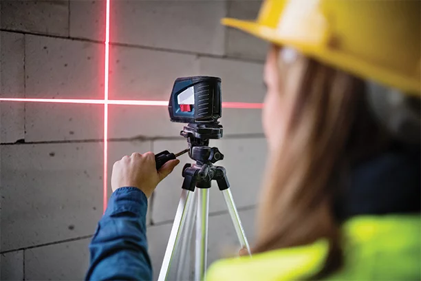 Woman wearing hi-vis and a hard hat using a laser level 