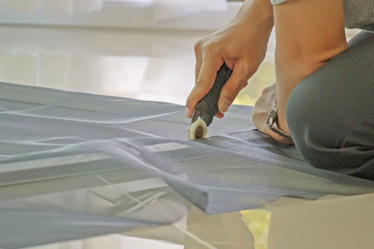 Person cutting out mesh for a screen window