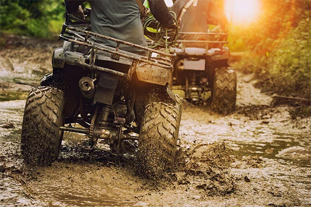 People riding ATVs through muddy water