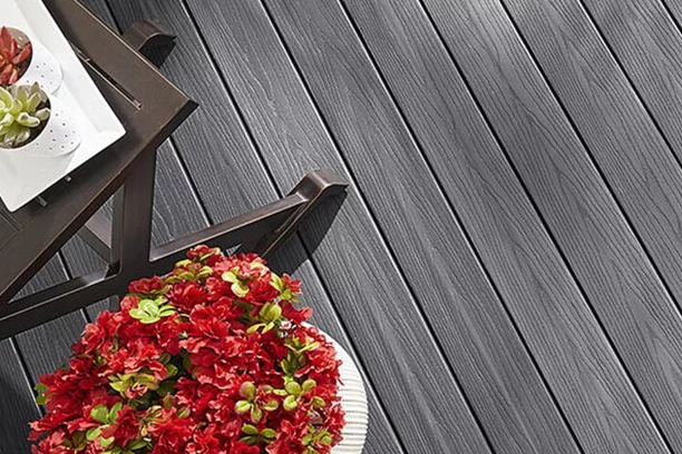 Top-down view of a deck with a brown side table and flower pot with red flowers