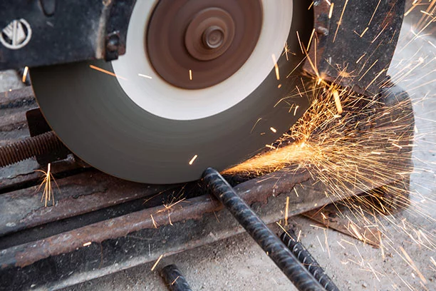 Somebody actively cutting a piece of rebar with a saw