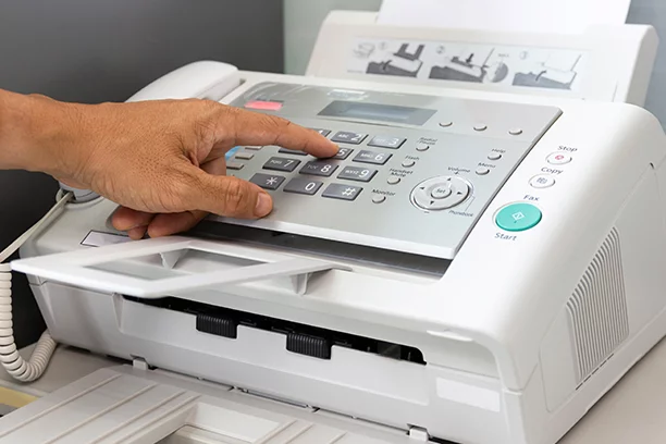 Close-up image of someones hand punching in number to a fax machine