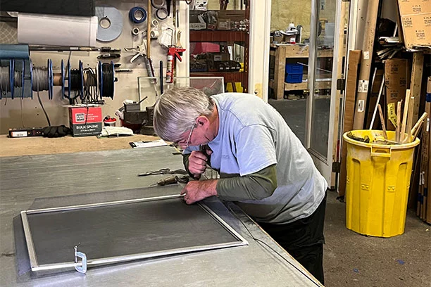 An employee repairing a window screen 