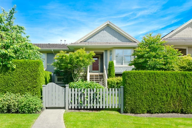 House with hedges, fence, and trees for privacy