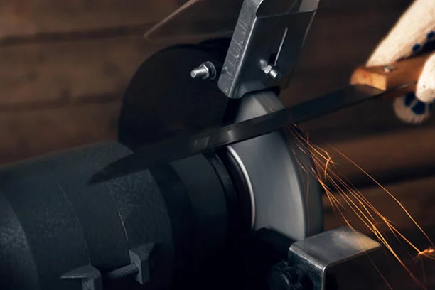 Person sharpening a knife blade on a grinder