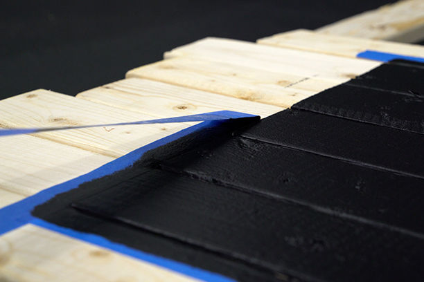 Closeup removing masking tape from wood boards