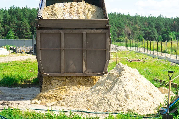 Dump truck delivering sand and dumping into a pile