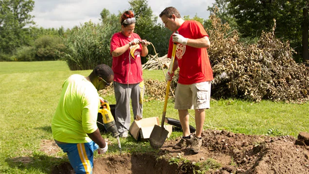 Three Valu volunteers digging a hole
