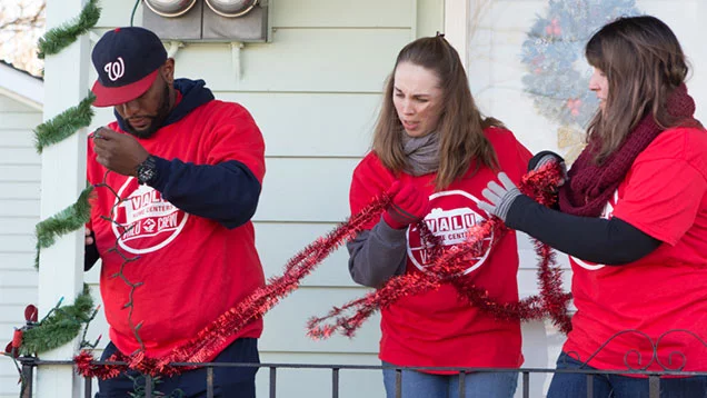 Valu Crew volunteers putting garland on handrail