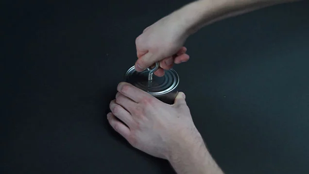 Screwing an eye hook into the top of the can where you drilled the hole