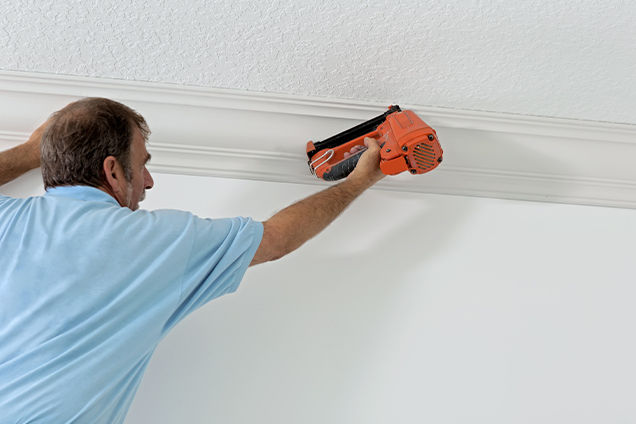 A man installing crown moulding