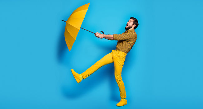 Man holding umbrella against wind