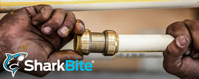 Text left - SharkBite logo - Image right - A person holding a pipe with SharkBite pipe connector on the end