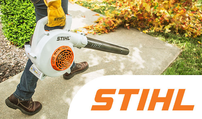 Stihl - Middle aged man using a STIHL gas powered blower to clear leaves off a sidewalk