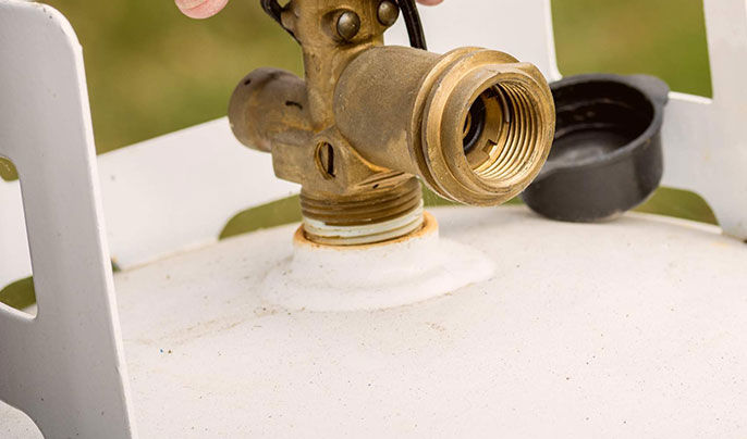 Close-up of a propane tank with grass in the background blurred