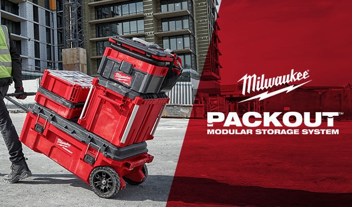 Lifestyle of a construction worker wearing a hi-vis vest rolling a Milwaukee PACKOUT system behind with the Milwaukee Packout logo on the right with red in the background