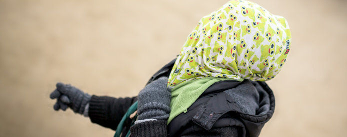 a person with a colorful scarf with frog prints over a mand head protecting it from potential harm