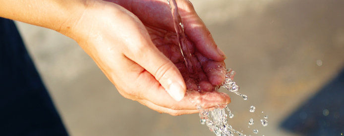 A close up of a lady washing her hands under a sink 