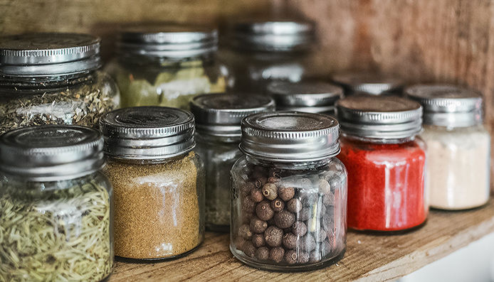 Different herbs and spices stored in glass jars in the pantry