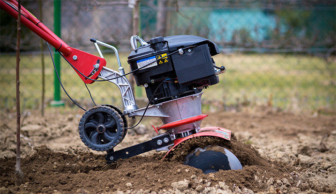 Side view of a garden tiller tilling soil