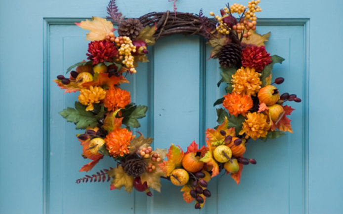 A fall floral wreath against a teal-blue front house door