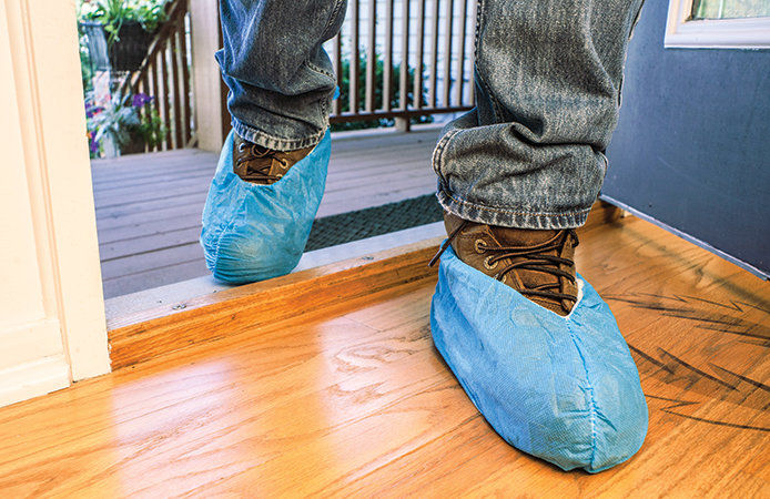 Person wearing protective covers over their shoes walking into a house