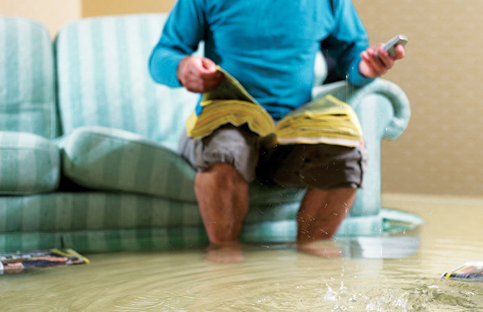 Man sitting on his couch with water up to his ankles