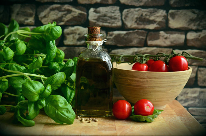 Tomatoes and basil on a kitchen countertop in a dark setting