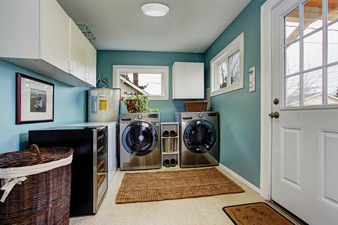 A teal painted laundry room with stainless steel washer and dryer 