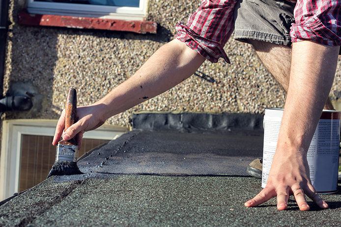 A person putting a coating on a roof