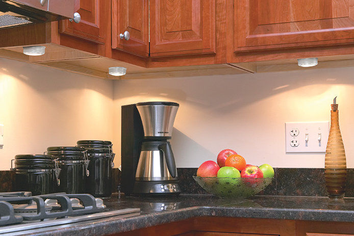 Kitchen counter with coffee pot and a bowl of fruit on the counter