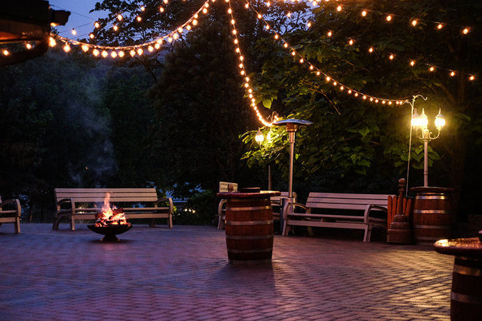 Patio sting lights hung in a public area with park benches and a firepit in the center 