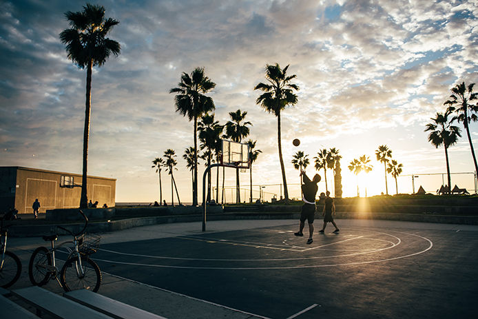 Two people playing basketball outside