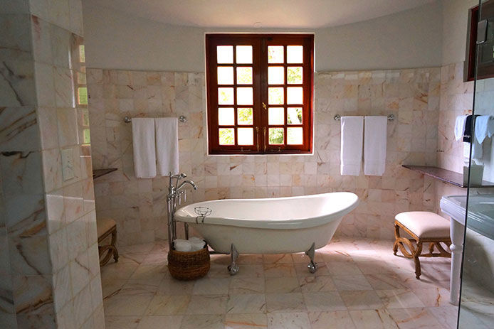 A white clawfoot tub in a tiled bathroom. 