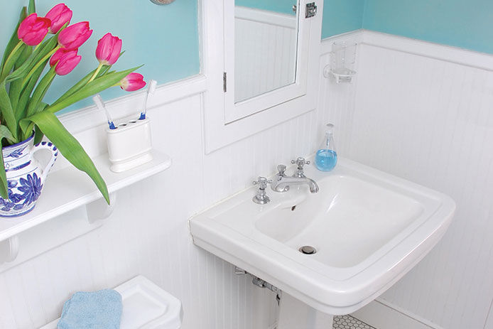 A bright bathroom wiht porcelain fixtures and tulip flowers as an accent piece 