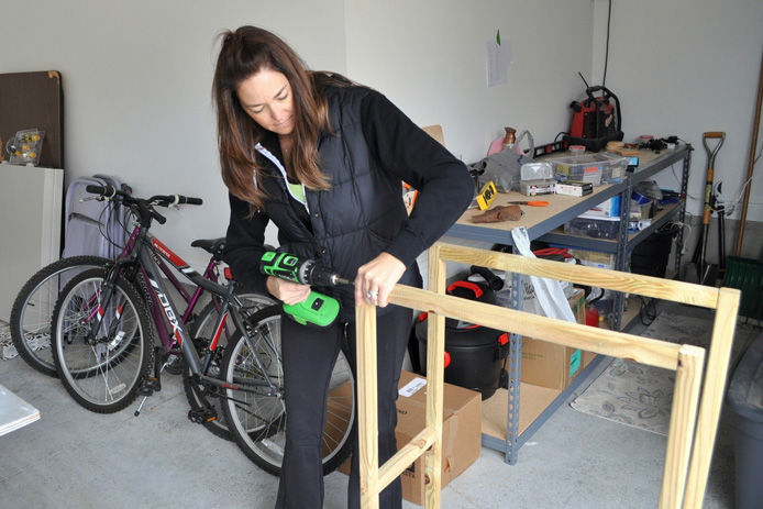 woman using drill to screw the fire log holder frame together