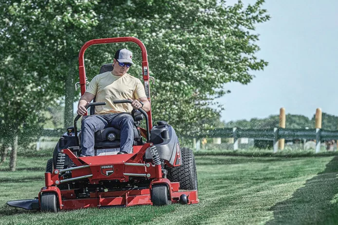 Person on ferris zero turn lawn mower cutting grass