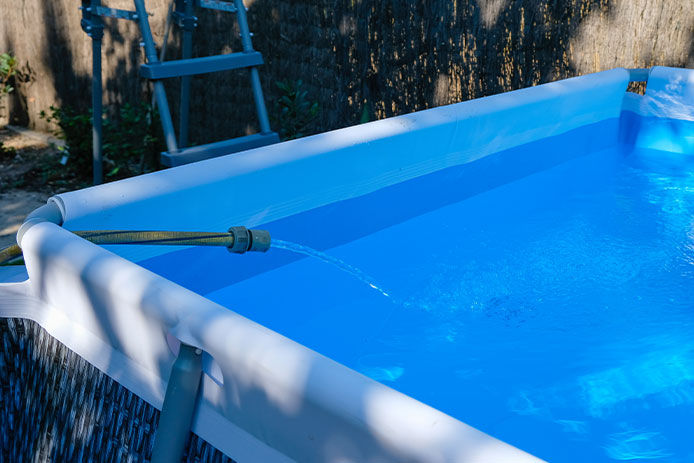 A hose filling an above ground pool with water