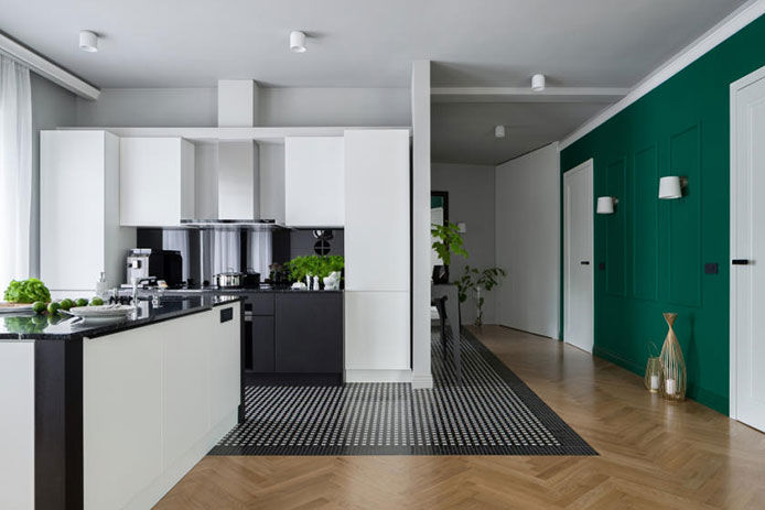Green accent wall opposite white and black kitchen