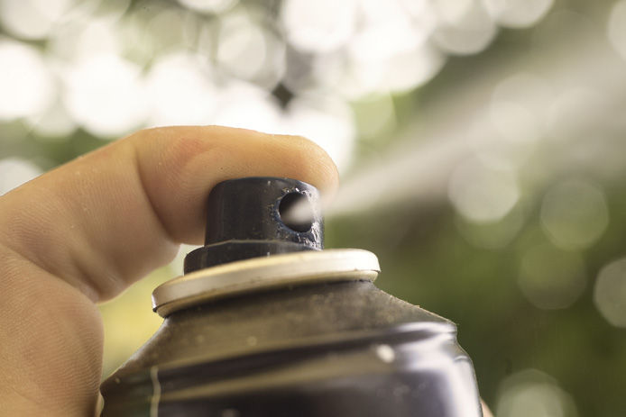 spray paint being sprayed for holiday diy decorations