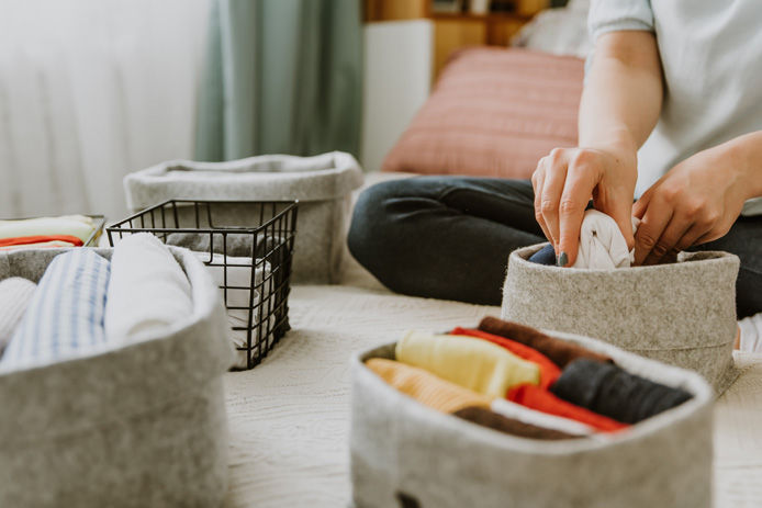 woman putting clothes into organizing bins