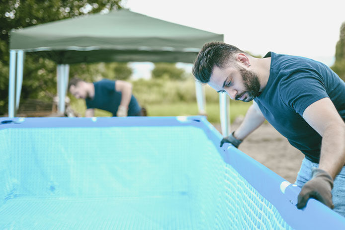 Two men installing the liner in an above ground pool