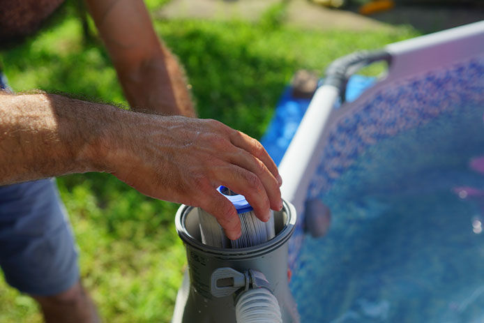 A person chaning the filter of an above ground pool