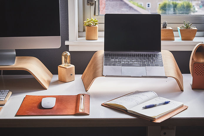 A at home computer desk with natural light shinning in a window with a date book and mouse